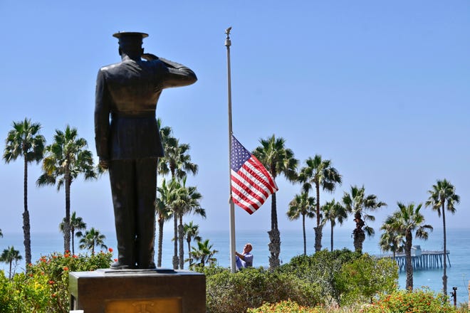 Wayne Eggleston lowers a U.S. flag to half-staff on Friday at Park Semper Fi in San Clemente, California.
