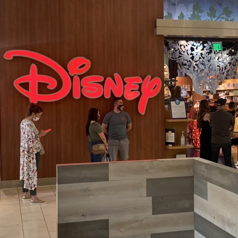 Shoppers wait outside the Disney Store at the Oaks
