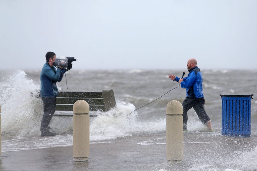 A news crew films as storm surge pushes water from Lake Pontchartrain over Lakeshore Drive as the effects of Hurricane Ida begin to be felt in New Orleans on Sunday, Aug. 29, 2021.    
