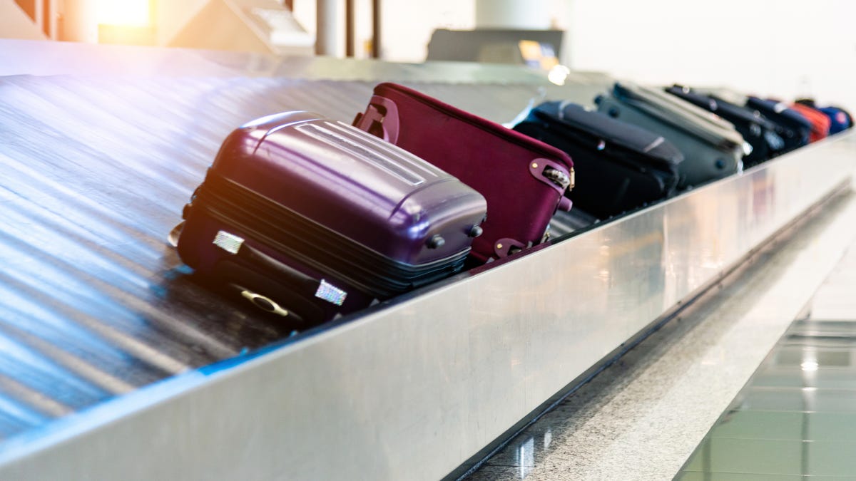 Luggage moves along on an airport conveyor belt.