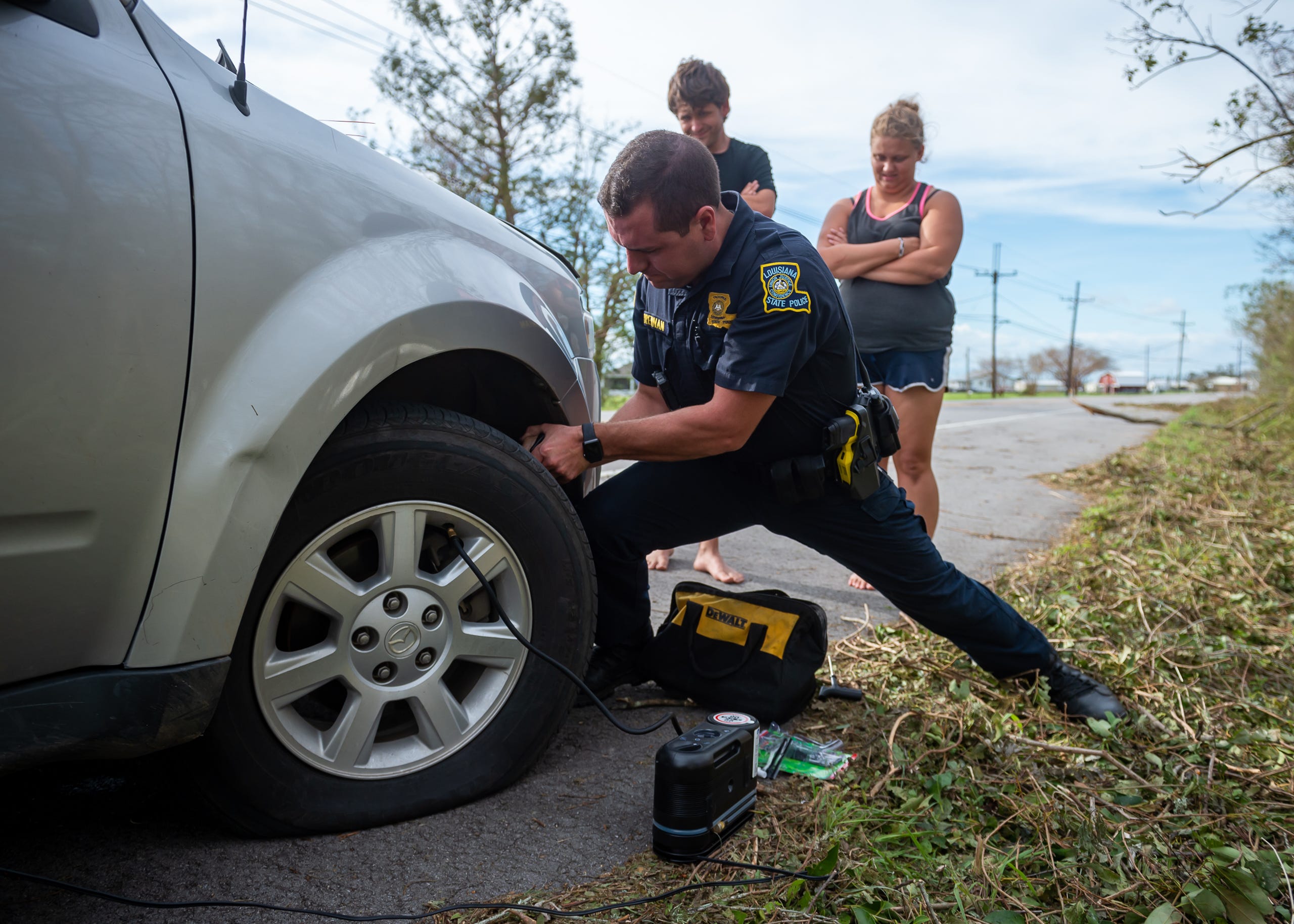 Louisiana State Trooper Ross Brennan assist motorist Justin Emmendorfer and Alexis Perry with changing and repaiiring a flat tire. Monday, Aug. 30, 2021.