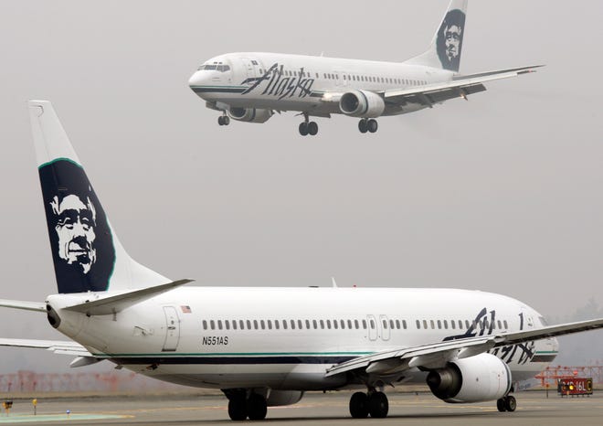 An Alaska Airlines plane comes in for a landing as another taxis for takeoff at Seattle-Tacoma International Airport in this file photo.