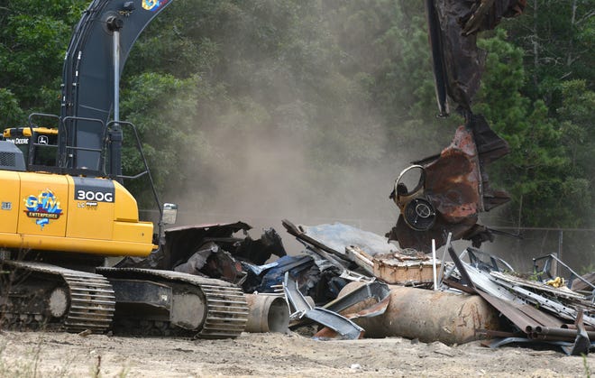 An excavator from GFM Enterprises picks through metal debris at the former Barnstable County Fire Training Academy on Monday. The site is being demolished because of the high level of PFAS contamination caused by training exercises.