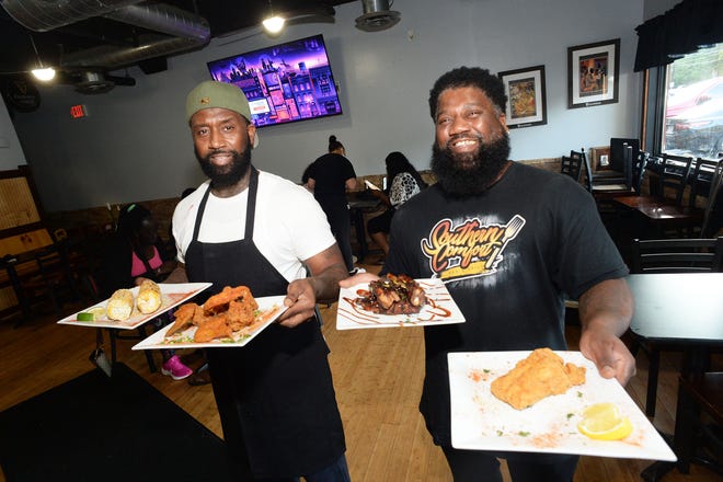 Co-owners Tony Wiggins-Rhodes, left, and brother Andre Wright-Rhodes, show off some of the dishes available at Southern Comfort Bar and Grill, 320 West Center St. in West Bridgewater, on Tuesday, Aug. 31, 2021.