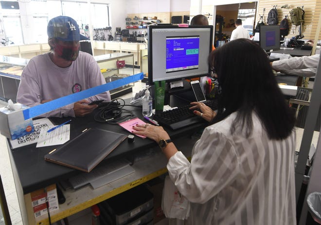 Robert Cutchin, left, pawns a laptop at National Pawn in Wilmington, N.C., Wednesday, September 1, 2021. The shop at 1702 Dawson St. opened in April after it had previously been Picasso Pawn.     MATT BORN/STARNEWS       