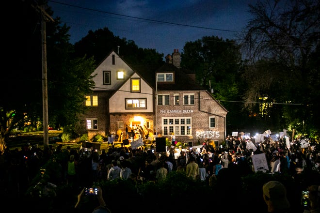 Hundreds of people hold signs and chant as a group pounds on the front door of the Phi Gamma Delta fraternity house during a protest, Tuesday, Aug. 31, 2021, in Iowa City, Iowa.