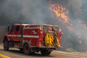 A Cal Fire engine drives by a burning tree in Twin Bridges, Calif., on Tuesday, Aug. 31, 2021. 