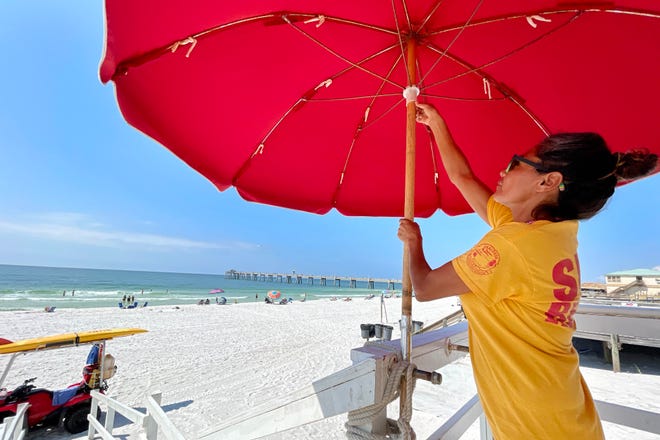 Anna Lee sets up an umbrella at the lifeguard station in front of The Boardwalk on Okaloosa Island Friday morning as she and the other lifeguards with Okaloosa County Beach Safety get ready for the start of the Labor Day weekend.