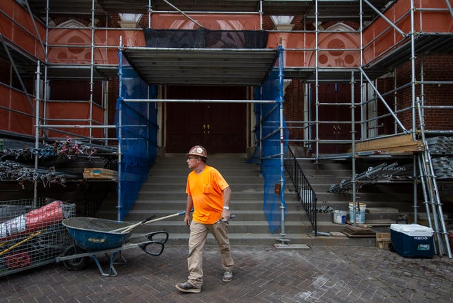 Tim Tanzillo walks past the entrance of St. Joseph Church in Louisville, Kentucky, which is undergoing an exterior renovation. July 19, 2021