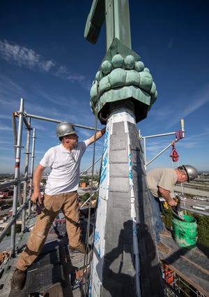 At 170 feet in the air Isaac Rader, left, and Roy Tackett, right replace the slate tiles on the east steeple of St. Joseph Catholic Church in Louisville. Sept. 3, 2021