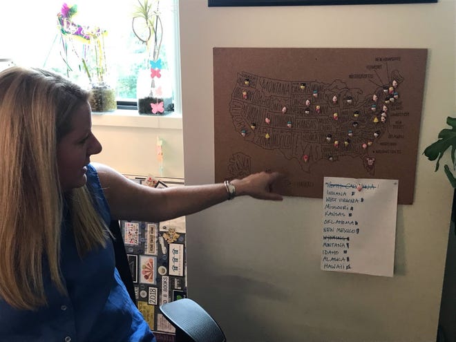 Amy Dwyer points to a map beside her office desk that shows where she has eaten ice cream across the U.S., marked off with pastel ice cream push pins.