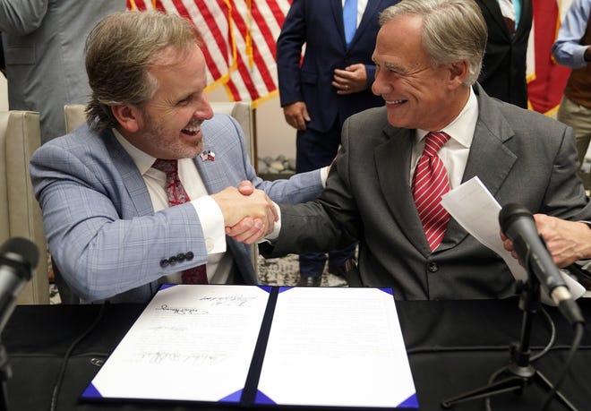 Gov. Greg Abbott and state Sen. Bryan Hughes, R-Mineola, shake hands after Abbott signed Senate Bill 1 into law last September. A federal judge has blocked a part of that elections law regarding vote-by-mail applications.