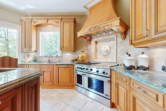 The main kitchen has a stone tile floor and carved European country-style cabinetry. The range is the commercial DCS brand.