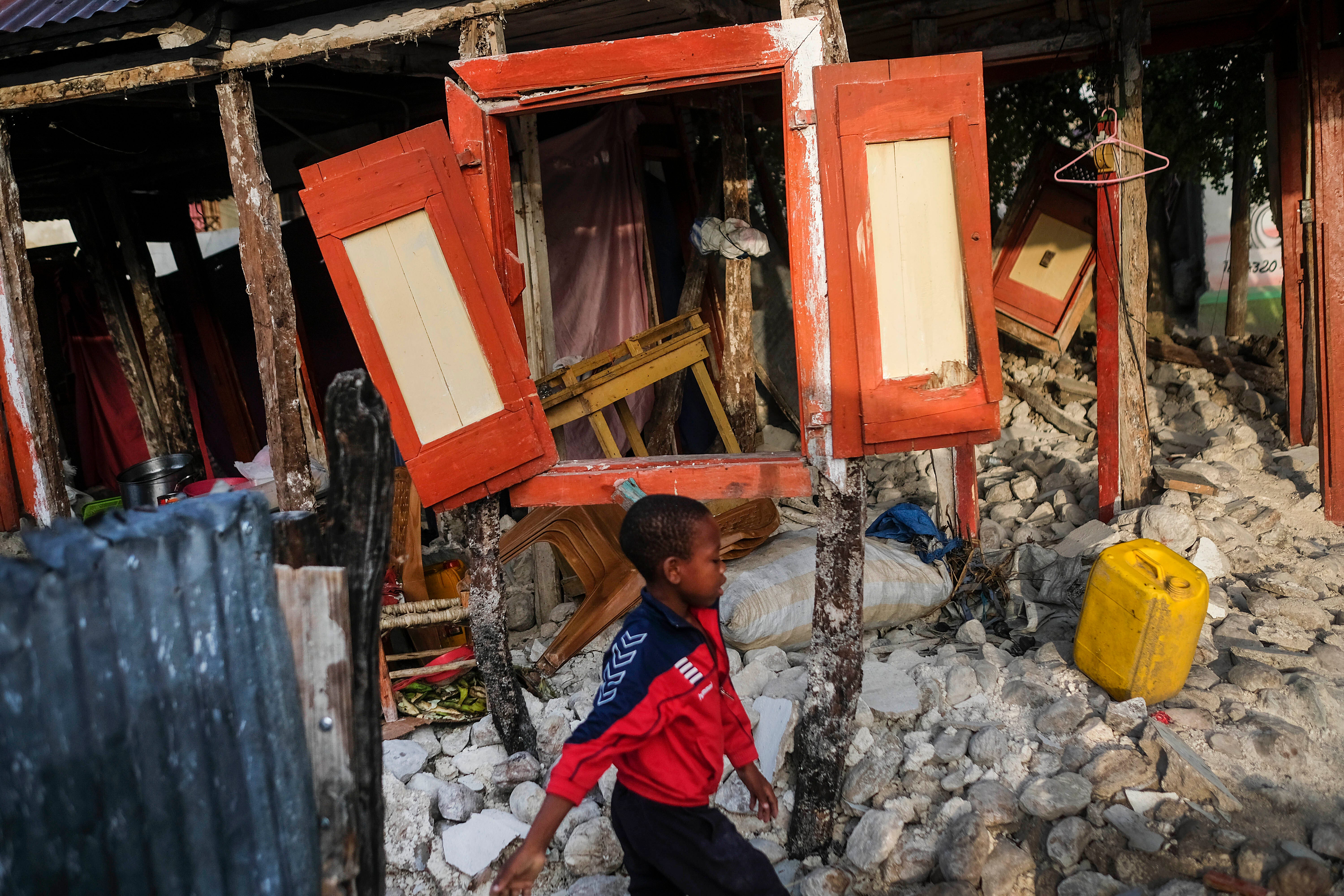 A boy walks past his home destroyed by the 7.2 magnitude earthquake, in Maniche, Haiti on Aug. 24, 2021.