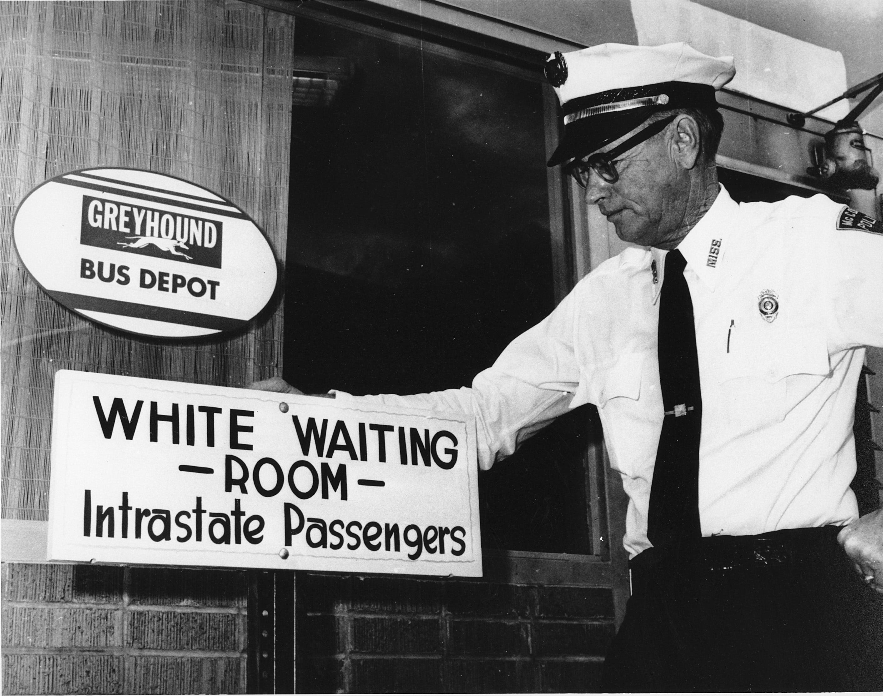 Police Chief George H. Guy poses beside the "White waiting room" sign posted outside the Greyhound bus terminal in McComb, Miss., on Nov. 2, 1961.