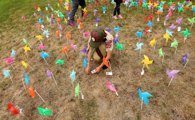 BSA Troop 1555 Scout Rowan Martin, 10, attaches a tag to a pinwheel commemorating the 20th anniversary of 9/11 while setting up the "Pinwheels for Peace" display at Village Green Park in Kingston on Friday. Each pinwheel represents 10 lives lost during the attacks on 9/11.