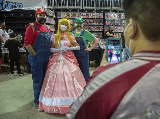 Kate Nystead of Stockton, left, her husband Corey Newstead and daughter Leo, dressed as Nintendo characters Mario, Princess Peach and Luigi, pose for a photo at Stockton Con 2021 at the Stockton Arena in downtown Stockton. 
