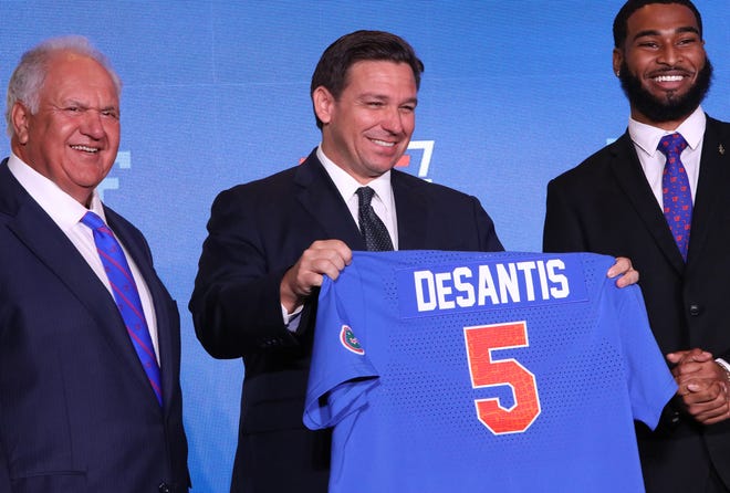Gov. Ron DeSantis holds up a jersey he received after the University of Florida was ranked among the top five publis universities in the country, during a ceremony at Alumni Hall on the UF campus in Gainesville on Sept. 13.