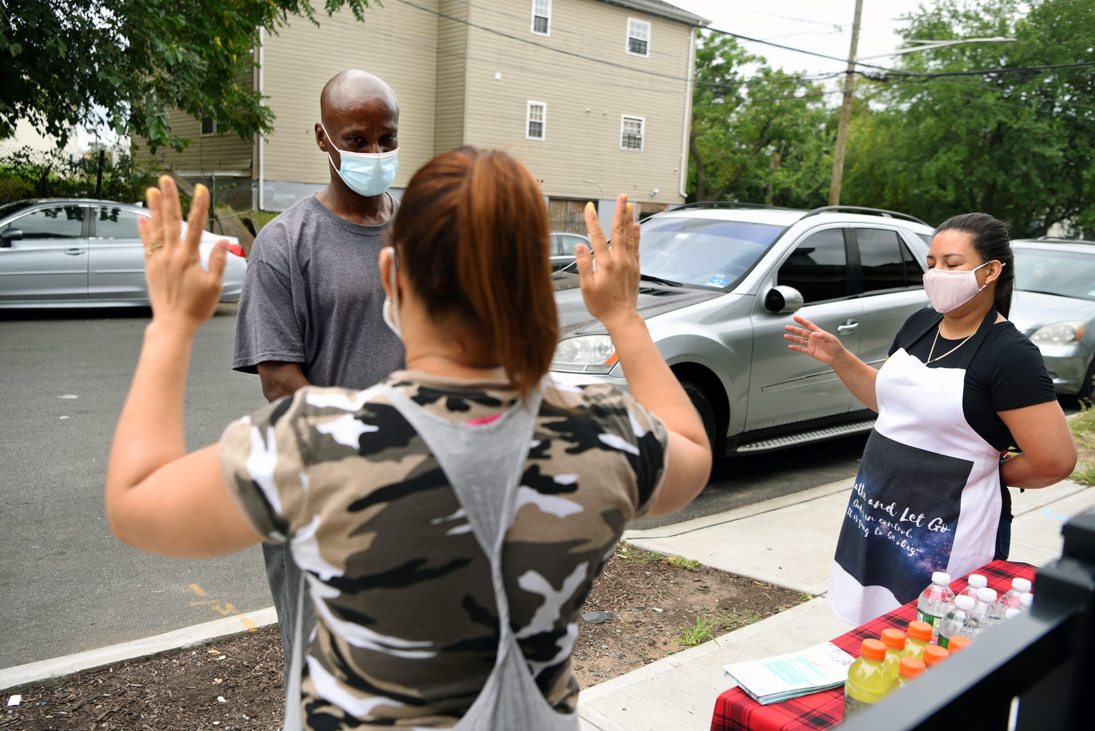 Neighbors Dafani Peralta and Jennifer Perez gather the last Saturday of the month to cook, pray and distribute food to those in  need in their new neighborhood. Perez leads a prayer on August 28, 2021.