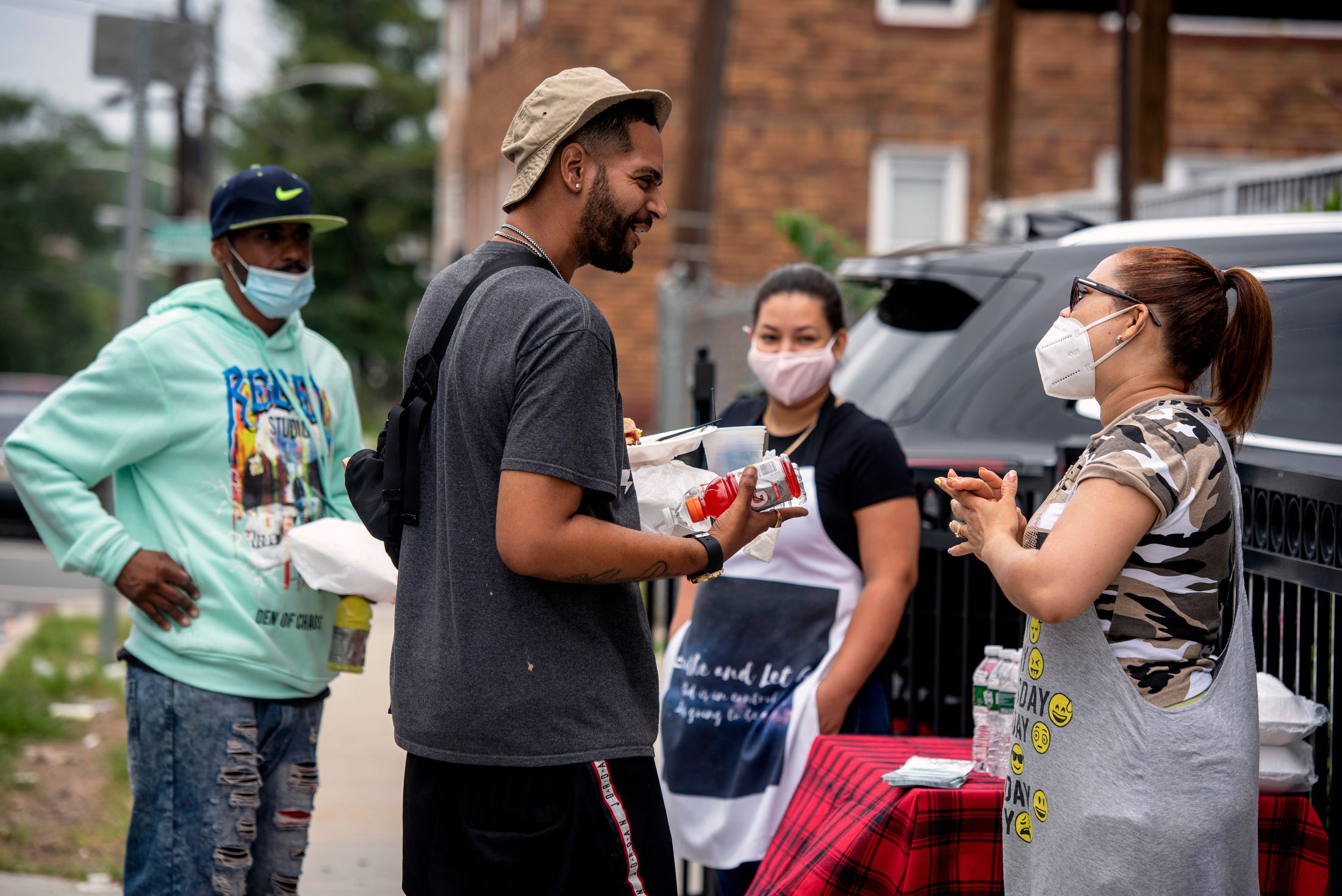 Neighbors Dafani Peralta and Jennifer Perez gather the last Saturday of the month to cook, pray and distribute food to those in need outside of their new homes on Hamilton Ave. in Paterson's 4th Ward. Bryan Rodriguez, 33 accepts lunch, some drinks and a prayer from Perez. Rodriguez is temporarily sleeping in his brother's car in Paterson.