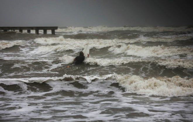 A surfer tries to paddle through the surf as wind and rain from Tropical Storm Nicholas batters the area Monday, Sept. 13, 2021, along the seawall in Galveston, Texas. (Jon Shapley/Houston Chronicle via AP)