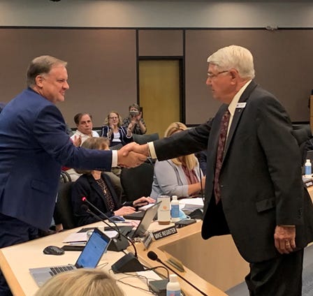 Michael Register (left), newly picked executive director of the St. Johns River Water Management District, shakes hands Tuesday with Douglas Burnett, chairman of the district's governing board.