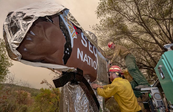 Firefighters from New Mexico wrap Sequoia National Park's iconic entrance sign on Tuesday, September 14, 2021. The spread of the KNP Complex Fire has closed the park and put areas of Three Rivers under evacuation warnings and orders. The sign, restored in recent years, has been at the entrance since 1935.