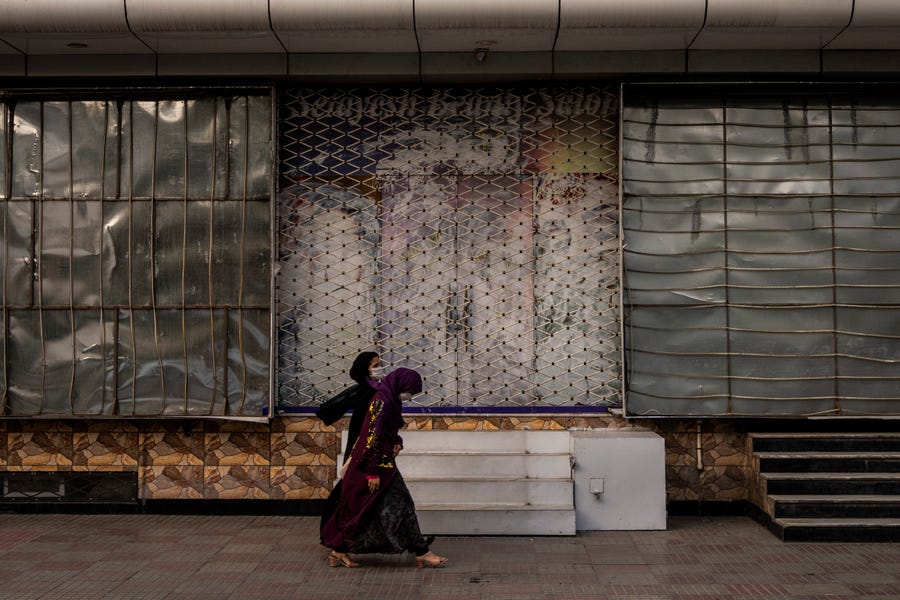 Afghan women walk past a closed beauty salon in Kabul, Afghanistan, Saturday, Sept. 11, 2021. Since the Taliban gained control of Kabul, several images depicting women outside beauty salons have been removed or covered up.