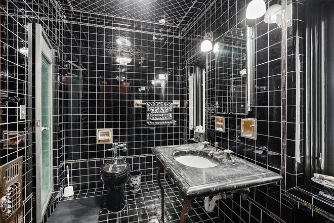 "His" share of the his-and-her baths in the owners' suite is finished in black tile and marble, including the ceiling.  Slim bronze legs support the shaving sink.
