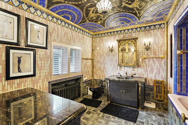 "Her" share of the his-and-her owners' baths is an extravagant art deco style, created from about 12 different art tile designs. The same slim bronze legs support her marble sink.
