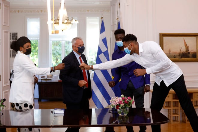 Bucks forward Giannis Antetokounmpo, right, fist bump with his mother Veronica after a naturalization ceremony Sept. 16, as his brother Alex Emeka and Greek Interior Minister Makis Voridis looks on at the Maximos Mansion in Athens.