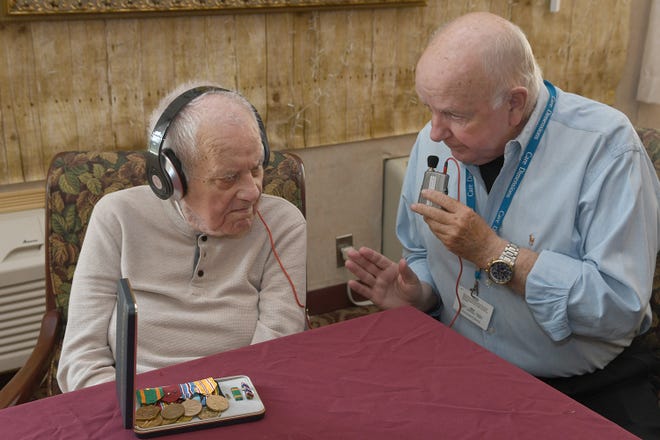 Care Dimensions, a provider of hospice care, will hold online training classes for those interested in becoming volunteers for the nonprofit organization. Pictured is volunteer Jerry Dunn speaking to a patient via a listening device.