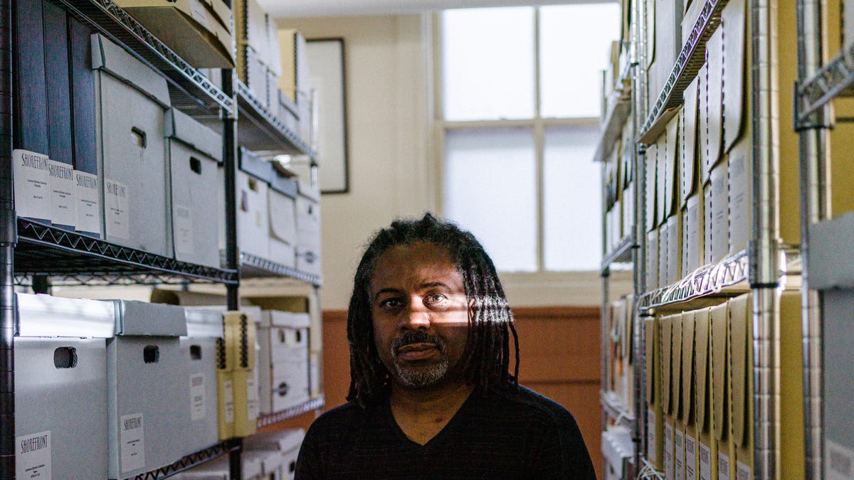 Morris "Dino" Robinson, the executive director of the Shorefront Legacy Center in Evanston, Ill., stands in between archived boxes and files. Robinson's organization provided city leaders most of the documentation of Evanston's longstanding housing discrimination as the city seeks reparation for many of its Black homeowners.