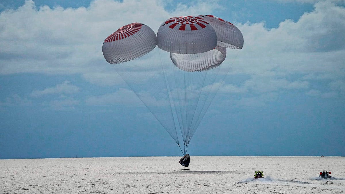 In this image taken provided by SpaceX, a capsule carrying four people parachutes into the Atlantic Ocean off the Florida coast, Saturday, Sept. 18, 2021. The all-amateur crew was the first to circle the world without a professional astronaut.