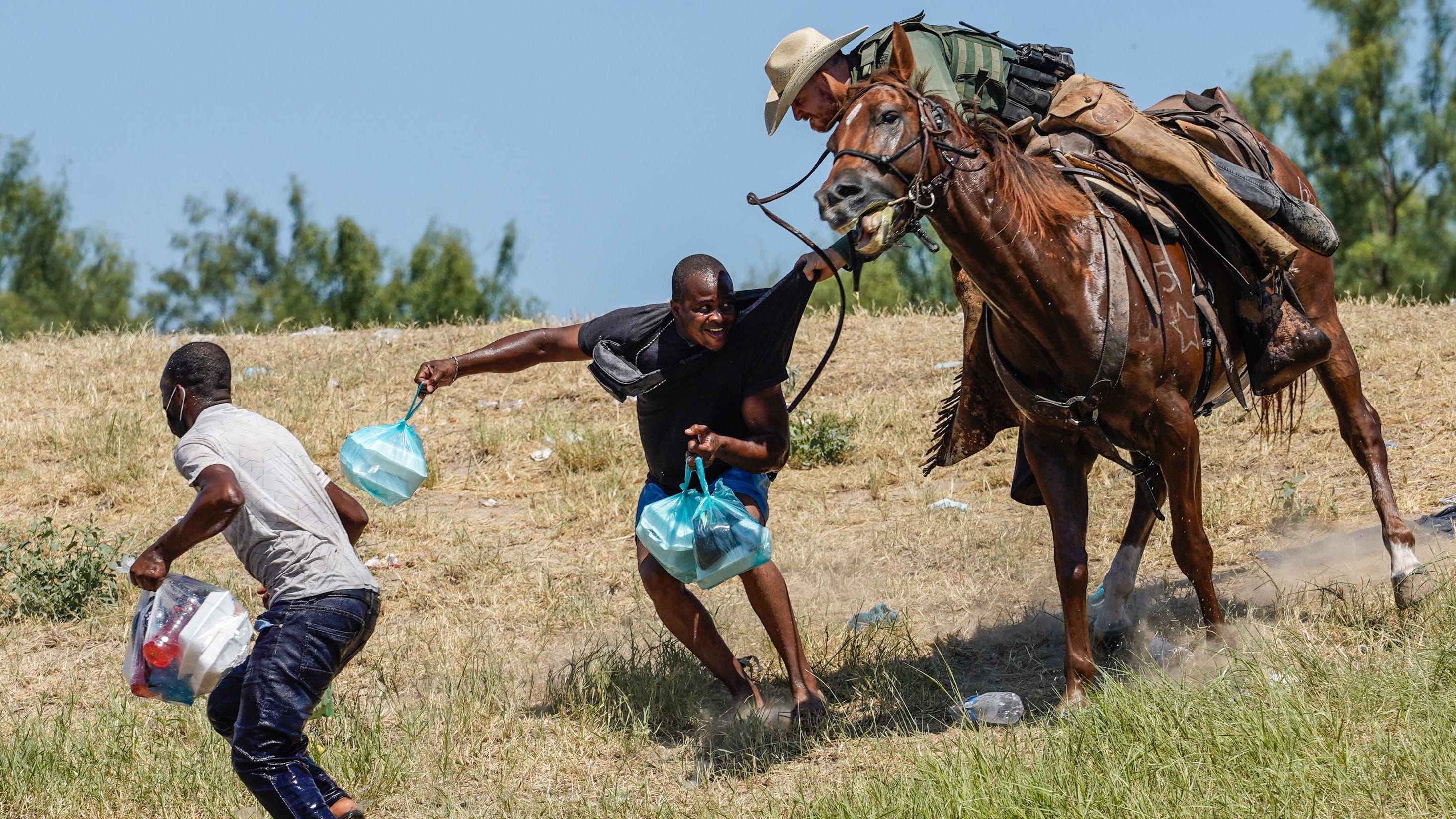 A U.S. Customs and Border Patrol agent on horseback tries to stop a Haitian migrant from entering an encampment on the banks of the Rio Grande in Del Rio, Texas, on Sept. 19, 2021.