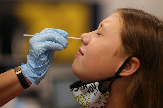 Lexus Walter has her nose swabbed by Susie Mathis at Moore High School in Louisville, Ky., on Aug. 19.  The school was one of several in the district offering coronavirus testing for staff and students.