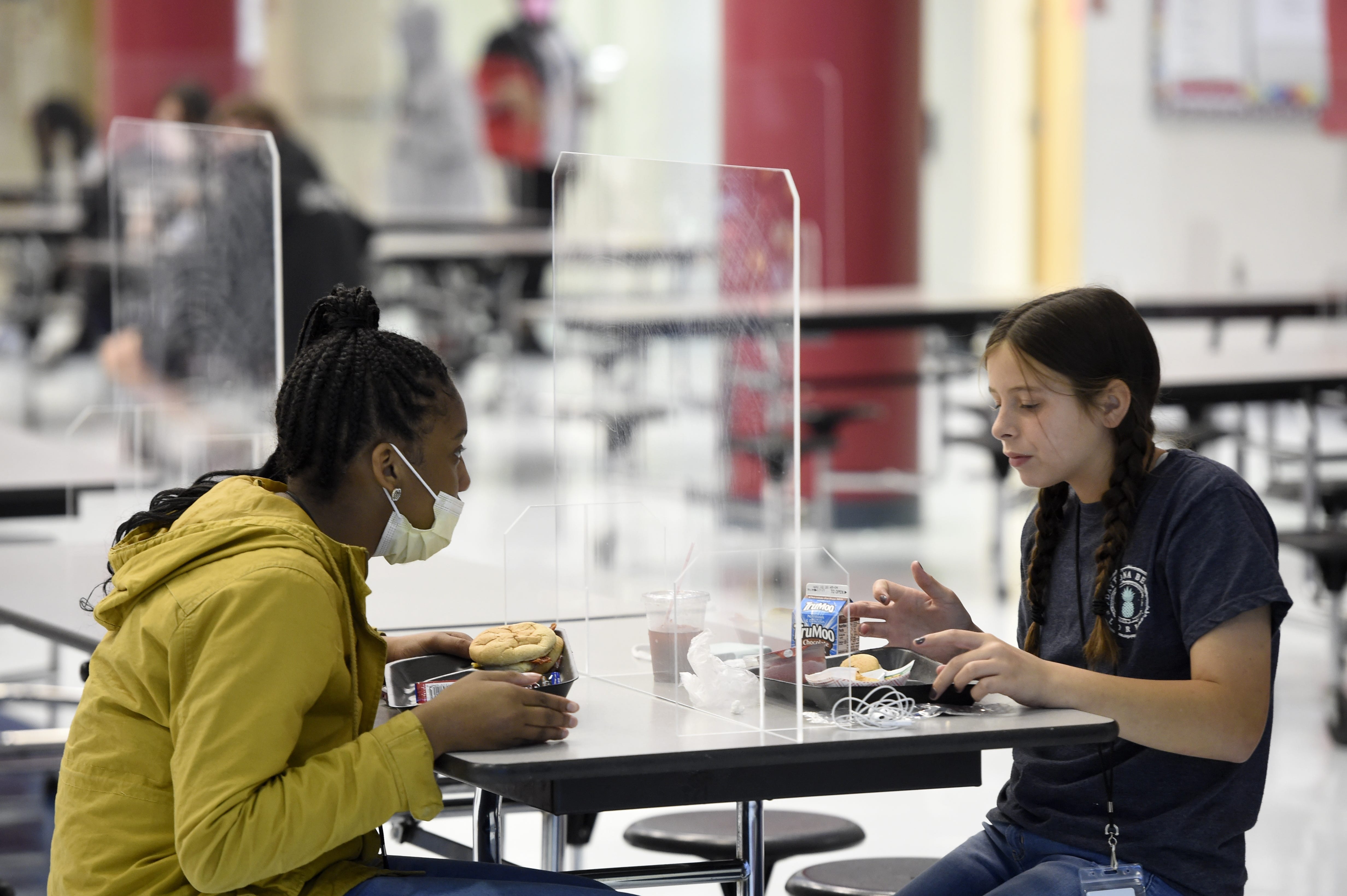 Students eat lunch while separated by clear dividers, so they can socialize and eat without a mask at Grovetown Middle School in 2020 in Georgia.