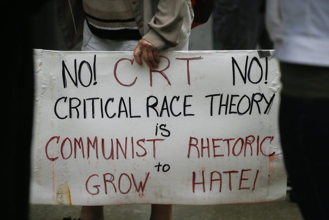 A protester against critical race theory curriculum in Ohio schools carries a sign on Tuesday, Sept. 21, 2021 outside the State Board of Education in Columbus, Ohio.