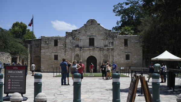 Tourists stands in front of the Alamo on Aug. 11, 