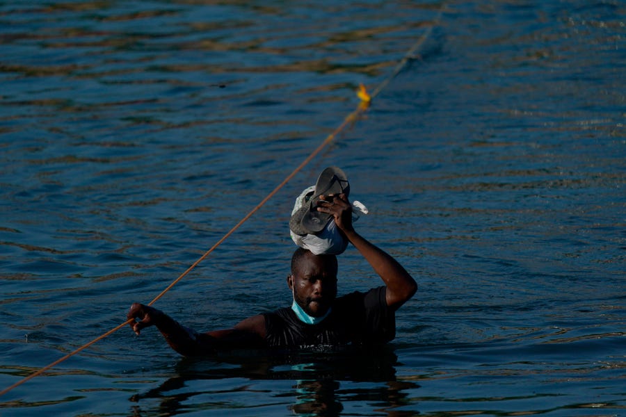 A Haitian migrant wades across the Rio Grande from Del Rio, Texas, to return to Ciudad Acuña, Mexico, Tuesday, Sept. 21, 2021, to avoid deportation from the U.S.