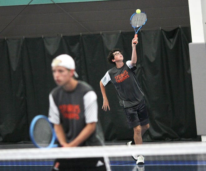 Adam Donmyer serves behind teammate Max Scheske in their match at first doubles inside Doyle Community Center on Wednesday.