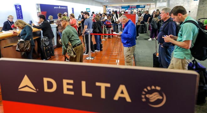 A moderate crowd lines up at the Delta counter at PBIA Monday. 