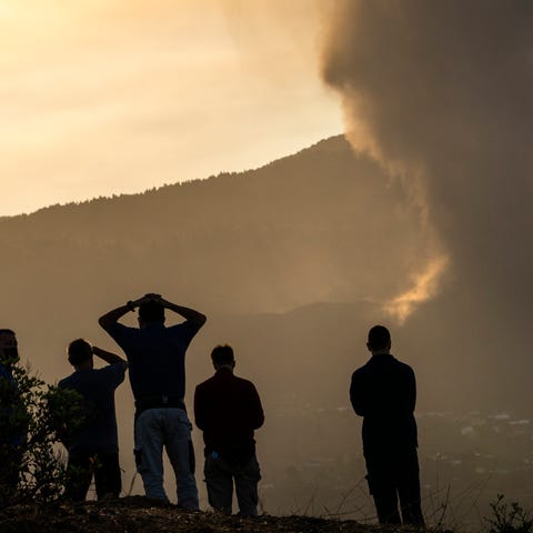 Residents look from a hill as lava continues to fl