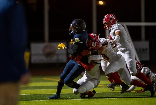 Jaiden Brown, #5, carries the ball as he is being tackled by three San Benito High School players during the Everett Alvarez High School varsity football game against the San Benito Haybalers in Salinas, Calif., on Friday, Sept. 24, 2021. 