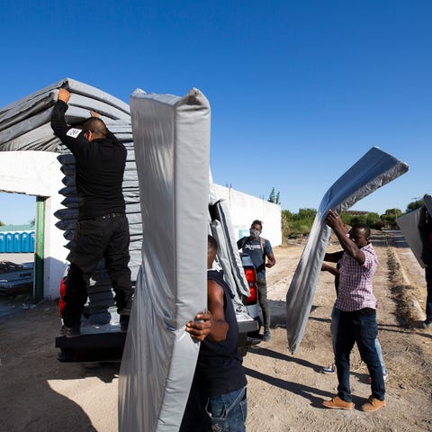 Haitian migrants unload cots at a new designated s