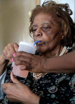 Lula Slayton, 84, who has dementia and uses a wheelchair is assisted with getting a drink by Melinda Howell, H.H.A., of Ohio Senior Home Health Care.
