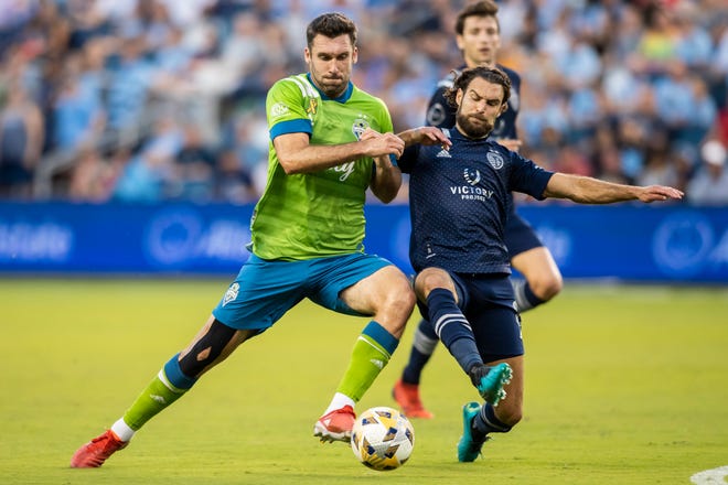 Sporting Kansas City midfielder Graham Zusi knocks the ball away from an attacking Seattle Sounders defender Will Bruin during a match in the 2021 season. Zusi is returning to Sporting KC for the 2022 season and has an option for 2023, the club announced Thursday.