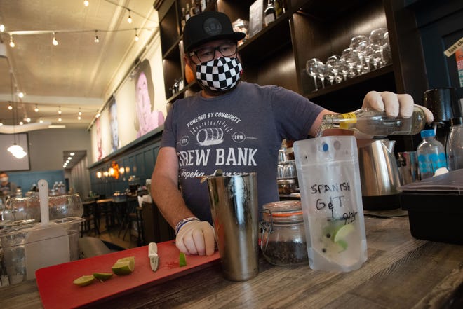 Ryan Cavanaugh, co-owner of Brew Bank, 822 S. Kansas Ave., pours in tonic water to top off a to-go version of the restaurants' Spanish Gin. Cavanaugh said adding the ability for to-go drinks has been good for his business, with custom cocktails being especially popular.