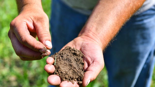 Farmer Jason Lorenz holds a handful of soil from a