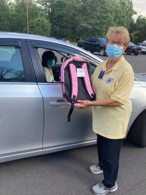 Karen Mager, president of the Kiwanis Club of Greece, delivers a backpack filled with supplies purchased through Dollar Days.
